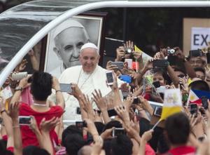 Pope Francis passes past a portrait of himself as he arrives to meet youths in Santo Tomas University in Manila, Philippines, Sunday, Jan. 18, 2015.